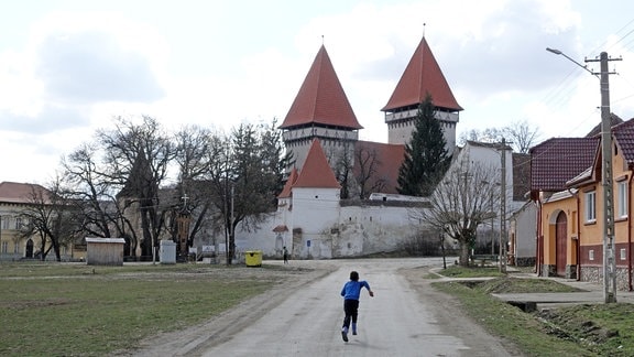 Eine Kirchenburg mit zwei Türmen am Ende einer Dorfstraße