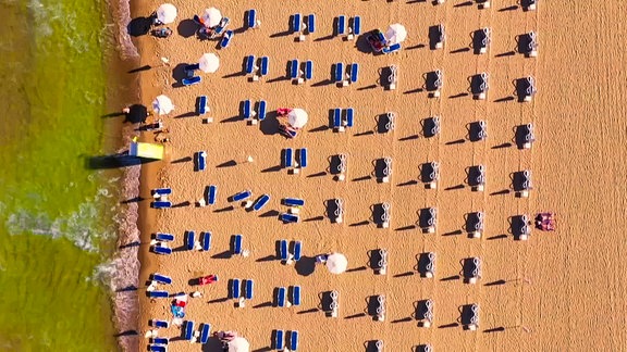 Strandliegen und Sonnenschirme am Sonnenstrand in der Draufsicht