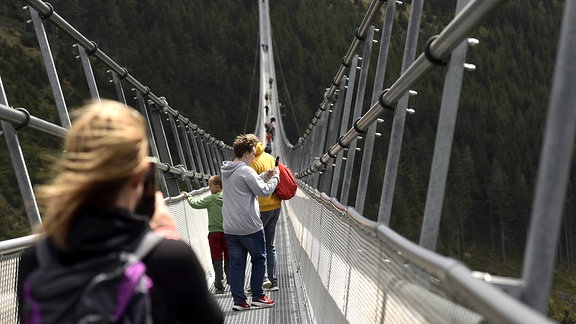 Menschen gehen über die kürzlich eröffnete, längste Fußgänger-Hängebrücke inm tschechischen Dolni Morava