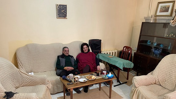 Ein älterer Mann und seine Frau sitzen zusammen auf einem Sofa.