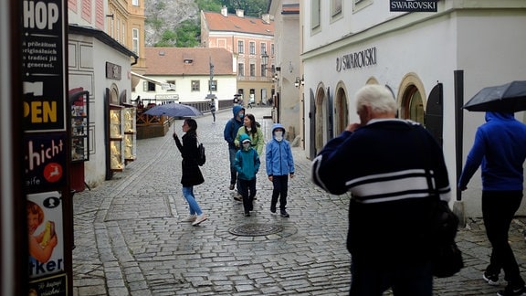 Menschen laufen im Regen durch eine Stadt