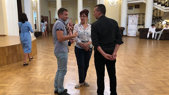 Theaterdirektor Sergej Dorofeev unterhält sich mit Projektorganisator Peter Schwarz und einer Mitarbeiterin.