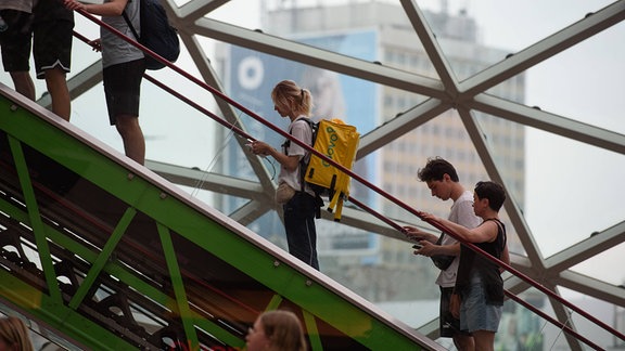 Menschen stehen auf einer Rolltreppe.