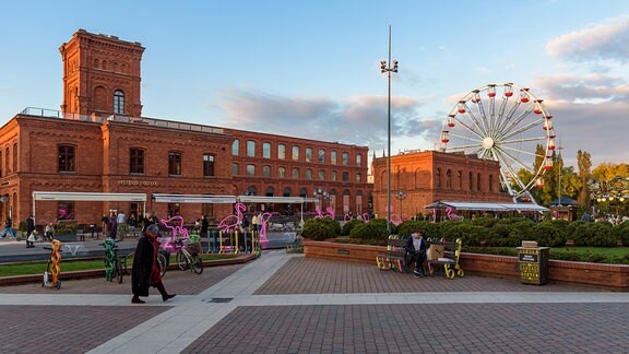 Menschen besuchen 2022 den inneren Platz von Manufaktura in Łódź