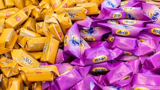 Polské karamelové bonbóny ve žluté a fialové leží na hromadě.