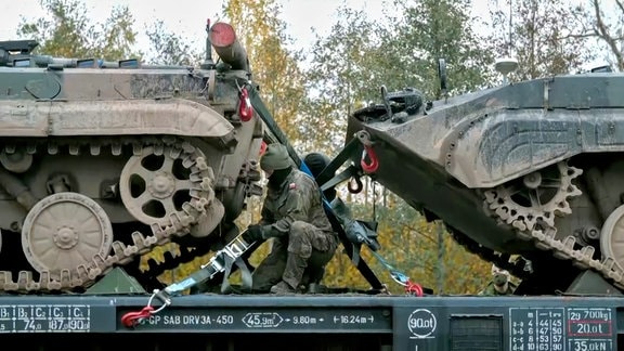 Soldat verzurrt Panzer mit Spanngurten auf Panzerzug