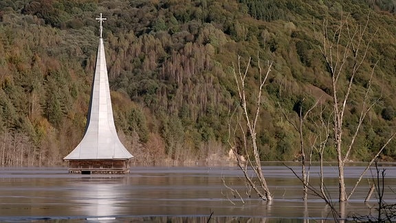 Ein Kirchturm ragt aus dem Wasser heraus.