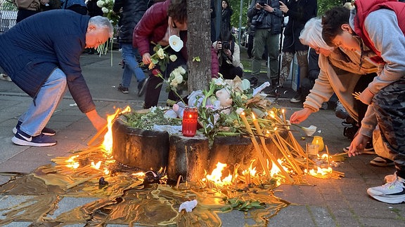 Menschen legen vor Schule in Belgrad Blumen nieder und zünden Kerzen an