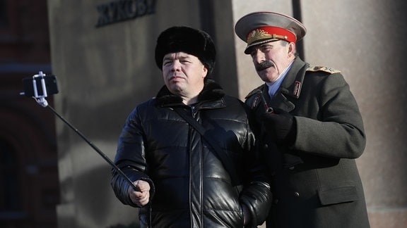 Mann fotografiert sich mit Stalin-Darsteller in Moskau. 