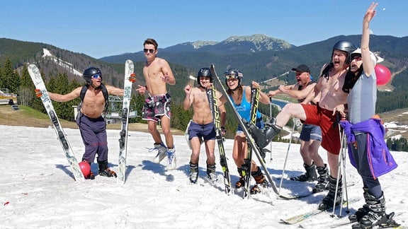 Leicht bekleidete Touristen posieren für ein Foto auf einem schneebedeckten Hang beim Abschluss der Saison 2017/2018 im Skigebiet Bukovel in den Karpaten, Gebiet Iwano-Frankiwsk