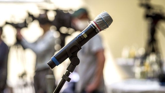 Ein Mikrofon mit Plastikschutz vor Coronaviren auf einer Pressekonferenz.