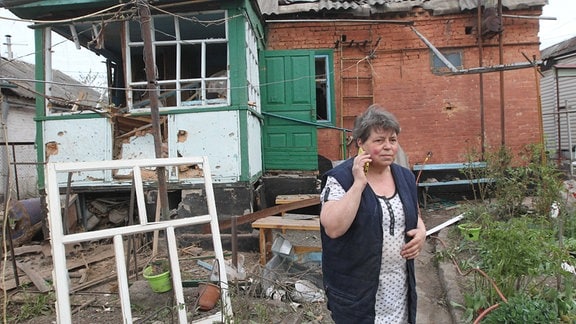 Eine Frau steht vor einem zerstörten Gebäude