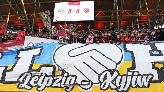 Transparent mit der Aufschrift  Rasenball hilft - Leipzig - Kyjiw  zur Unterstützung der Ukraine in blau-gelben Farben beim Spiel RB Leipzig gegen Frankfurt 