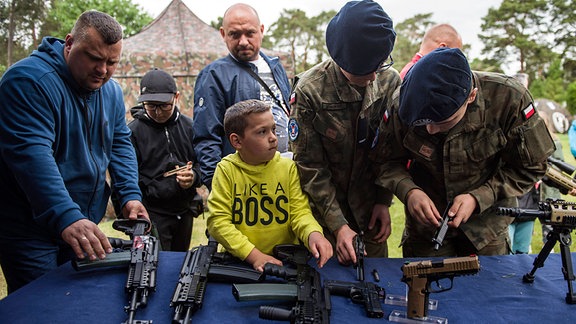 Kinder und Erwachsene probieren beim Militärpicknick Gewehre und Schusswaffen aus.