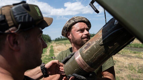 Ukrainische Soldaten laden eine Granate in eine Panzerhaubitze.
