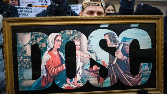 Demonstrant hält Bild mit Schriftzug aus Heiligengemälde.