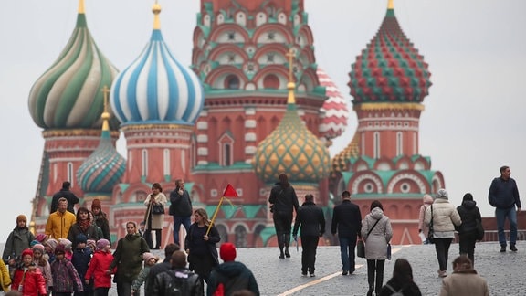Spaziergänger auf dem Roten Platz mit der Basilius-Kathedrale im Hintergrund.