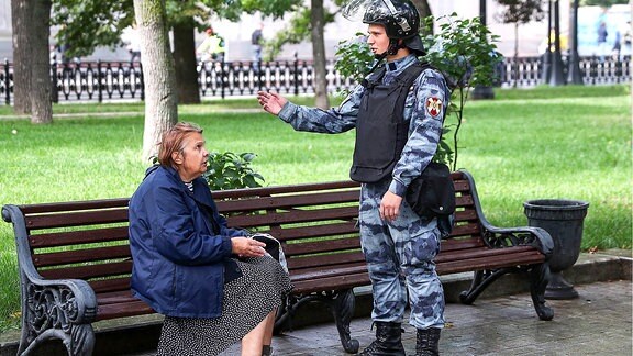 Eine Frau und ein Bereitschaftspolizist sprechen während einer Kundgebung in Moskau