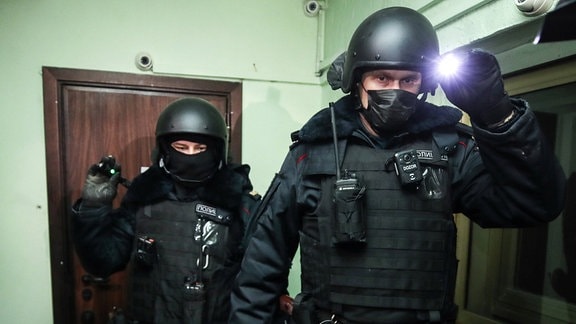 Polizisten in Helmen mit Lampe bei Durchsuchung von Wohnung von Nawalny in Moskau 