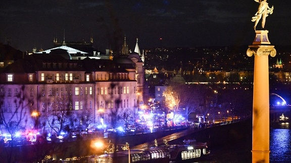 Feuerwehrfahrzeuge und Krankenwagen stehen am Ufer vor der Karls-Universität. An einer Hochschule in der Prager Innenstadt sollen Schüsse gefallen sein. 