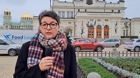 Ostbloggerin Vessela Vladkova steht mit Mikro in der Hand vor dem Parlamnetsgebäude in Sofia.