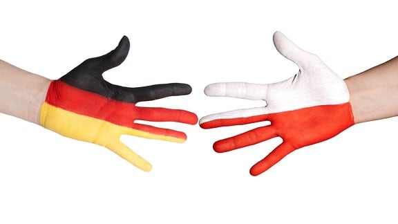 Zwei Hände, eine mit der Flagge Deutschlands, die andere mit der Flagge Polens