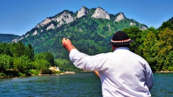 Flößer mit traditioneller Kopfbedeckung vor imposanter Bergkulisse, auf dem Dunajec in Polen.