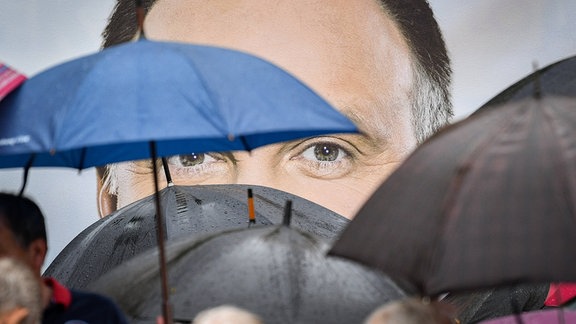 Andrzej Duda auf Plakat, vor dem Personen mit Regenschirmen zu sehen sind