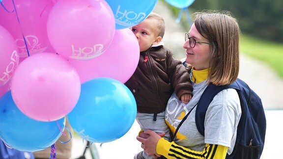 Frau mit Kind vor Luftballons.