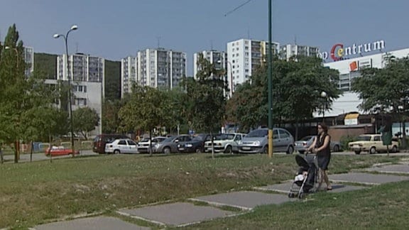 Eine Aufnahme aus dem Jahr 2004: Eine Frau schiebt einen Kinderwagen. Im Hintergrund Plattenbauten.