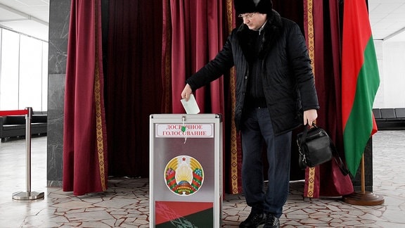 Ein mann wirft seinen Wahlzettel in eine Wahlurne.