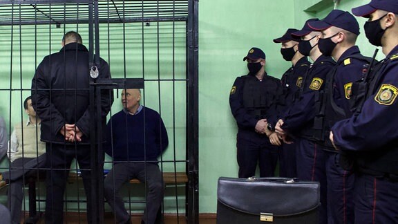 Vladimir Tsyganovich (links) und Nikolai Statkevich (dritter von links)  im Käfig der Angeklagten während einer Anhörung