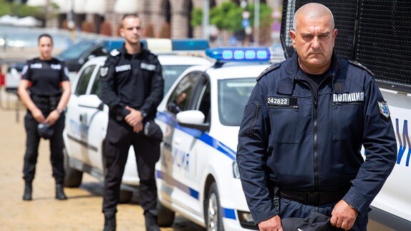 Polizisten neben ihren Autos