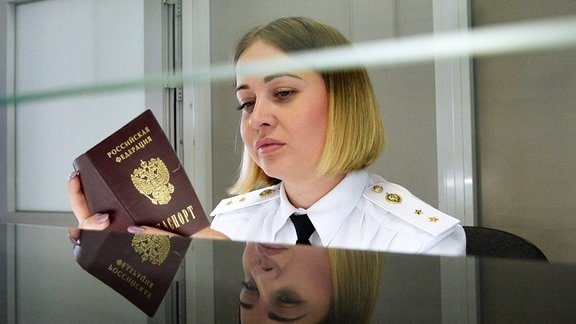 Eine junge Frau kontrolliert an einem russisch-kasachischen Grenzübergang einen Pass