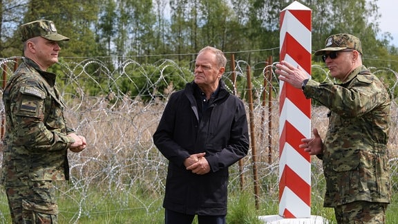 Donald Tusk (M), Ministerpräsident von Polen, der Oberbefehlshaber des Grenzschutzes, Generalmajor Robert Bagan (l) und der stellvertretende Befehlshaber des Grenzschutzes in Podlachien, Oberstleutnant Marek Sochanski, sprechen bei einem Besuch an der Grenze zu Belarus.