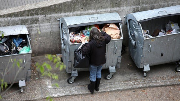Ein Mann durchsucht einen Müllcontainer
