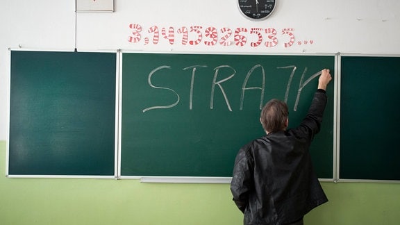 Ein polnischer Lehrer schreibt etwas an eine Tafel.