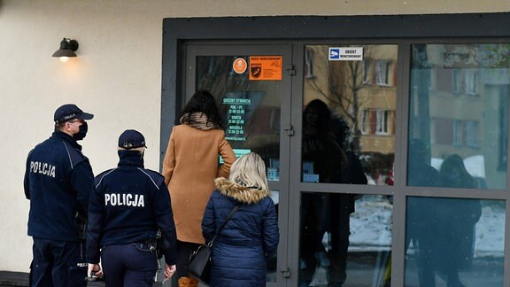 Polnische Polizei begleitet zwei Frauen in ein Haus