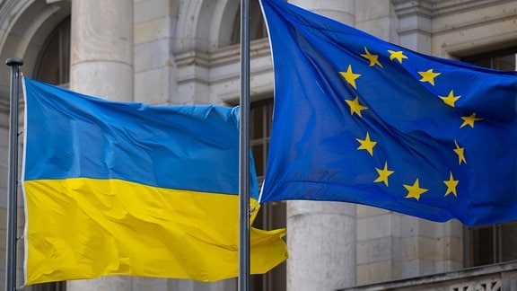 Die Nationalflagge der Ukraine und die Flagge der EU wehen im Wind.