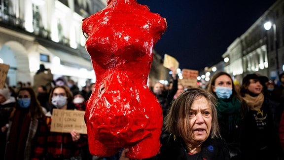 Eine rote Frauenkörperplastik wird auf einer Demosntration in die Höhe gehalten
