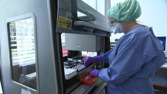Labormitarbeiterin entnimmt Blutproben in Reagenzgläsern