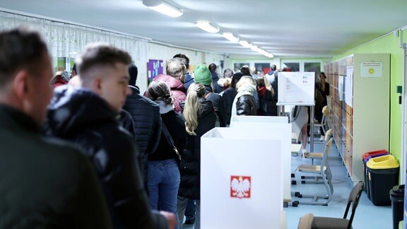 Menschen stehen in einem polnischen Wahllokal.