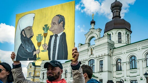 Ein Demonstrant hält eine Karikatur von Putin und Kirill, dem Moskauer Patriarchen und Oberhaupt der Russischen Kirche, im Eingang des Höhlenklosters Petschersk Lavra in Kiew.