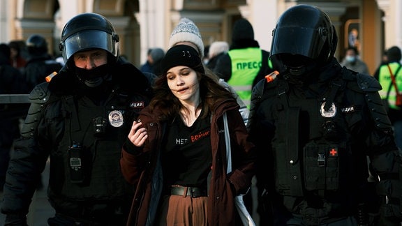 Polizisten führen junge Frau ab.