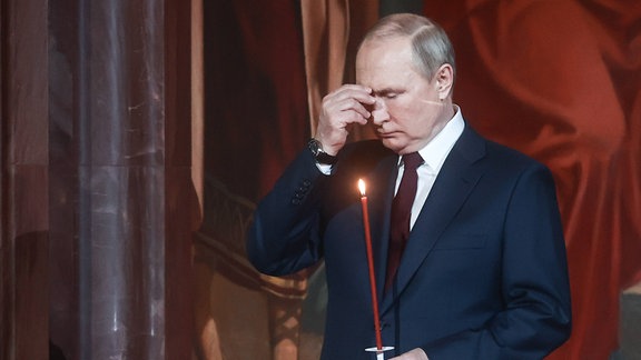 Präsident Wladimir Putin hält eine Kerze.