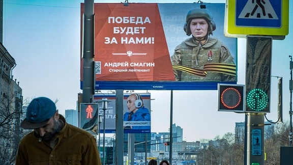 Großflächige Anzeigetafel mit dem Bild des russischen Oberleutnants Andrej Smagin und der Überschrift "Der Sieg wird unser sein." auf einem öffentlichen Platz in Moskau. 
