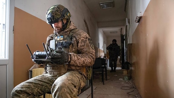 Der ukrainische Drohnenpilot Leonid sitzt in einem Gang auf einem Stuhl.