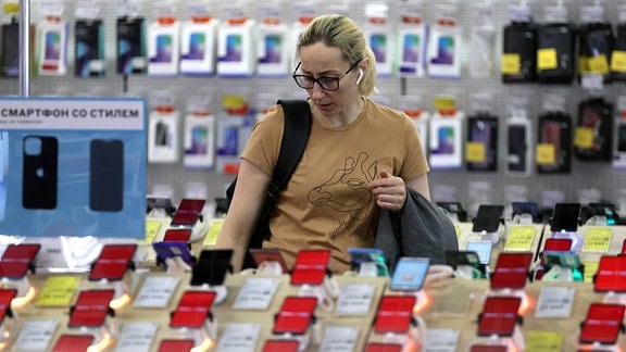 Eine Frau betrachtet Smartphones in einem Elektronikgeschäft.