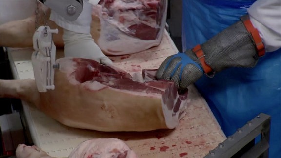 Fleisch-Zerleger arbeitet am Fließband in einem Schlachthof