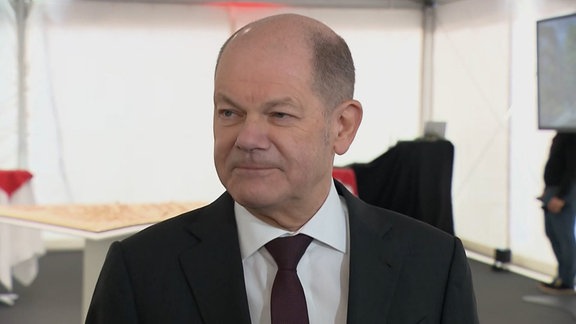 Bundeskanzler Olaf Scholz in einem weißen Zelt im Porträt.